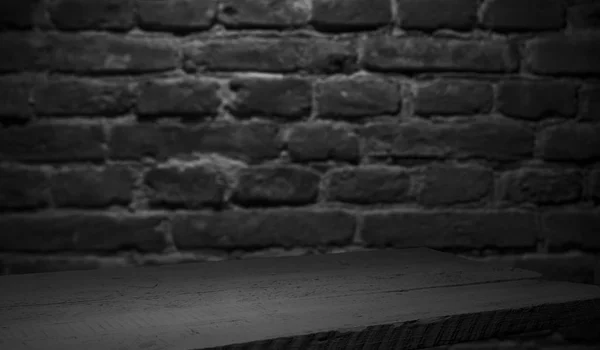 Old wood table with blurred concrete block wall in dark room background. — Stock Photo, Image