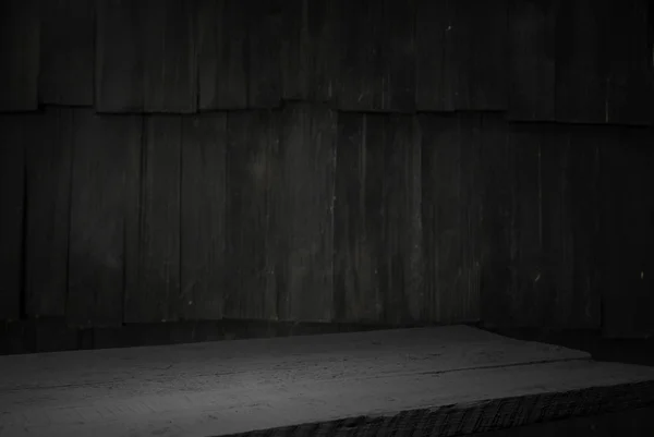 Old wood table with blurred concrete block wall in dark room background. — Stock Photo, Image