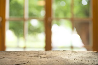 Ağaç bahçe arka planda pencere görünümü yeşil ile perde bulanıklık üzerinde ahşap masa üst boş. Montaj ürün gösterimi veya tasarım anahtarı görsel düzeni için