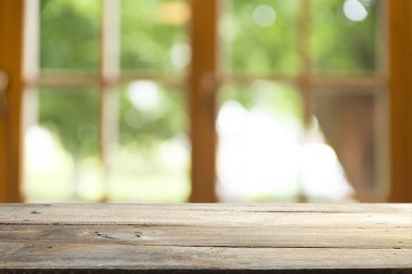 Ağaç bahçe arka planda pencere görünümü yeşil ile perde bulanıklık üzerinde ahşap masa üst boş. Montaj ürün gösterimi veya tasarım anahtarı görsel düzeni için