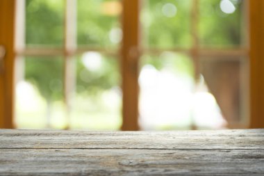 Ağaç bahçe arka planda pencere görünümü yeşil ile perde bulanıklık üzerinde ahşap masa üst boş. Montaj ürün gösterimi veya tasarım anahtarı görsel düzeni için