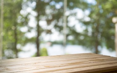 Ağaç bahçe arka planda pencere görünümü yeşil ile perde bulanıklık üzerinde ahşap masa üst boş. Montaj ürün gösterimi veya tasarım anahtarı görsel düzeni için
