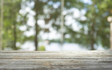 Ağaç bahçe arka planda pencere görünümü yeşil ile perde bulanıklık üzerinde ahşap masa üst boş. Montaj ürün gösterimi veya tasarım anahtarı görsel düzeni için