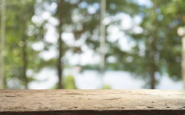 Ağaç bahçe arka planda pencere görünümü yeşil ile perde bulanıklık üzerinde ahşap masa üst boş. Montaj ürün gösterimi veya tasarım anahtarı görsel düzeni için