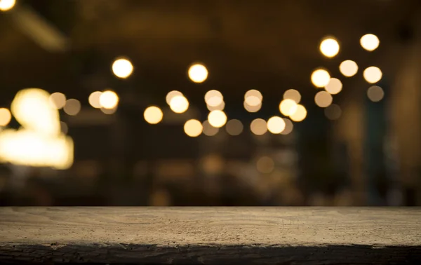 Empty wood table top on blur light gold bokeh of cafe restaurant in dark background — Stock Photo, Image