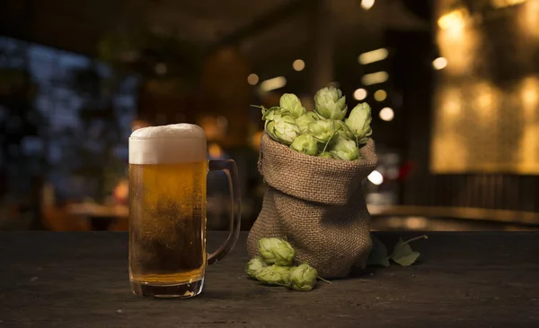 Beer brewing ingredients Hop in bag and wheat ears on wooden cracked old table. Beer brewery concept. Hop cones and wheat closeup. Sack of hops and sheaf of wheat on vintage background. — Stock Photo, Image