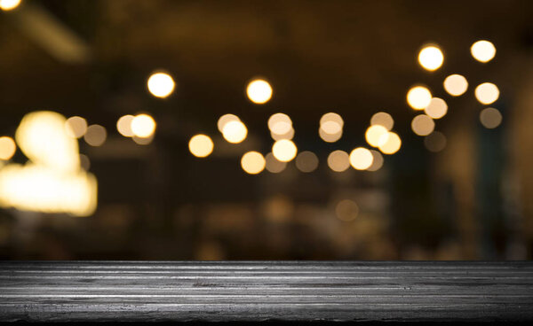Пустая столешница из дерева на размытом светлом золотом боке кафе ресторана на тёмном фоне
