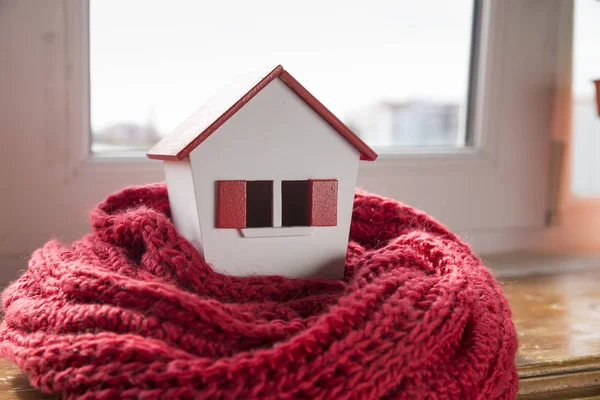House in winter - heating system concept and cold snowy weather with model of a house wearing a knitted cap — Stock Photo, Image