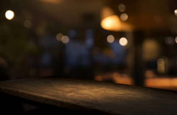 Prázdný dřevěný stůl nahoře na světle vyostřené zlaté bokeh Café Restaurant na tmavém pozadí — Stock fotografie
