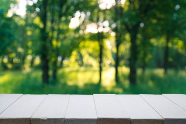 Park bokeh arkaplanlı boş ahşap güverte masası.