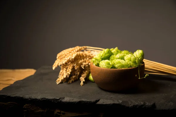 Beer. Still life with Vintage beer barrel and glass light beer. Fresh amber beer concept. Green hop and gold barley on wooden table. Ingredients for brewery. Brewing traditions