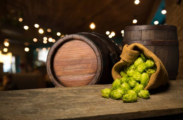 Beer. Still life with Vintage beer barrel and glass light beer. Fresh amber beer concept. Green hop and gold barley on wooden table. Ingredients for brewery. Brewing traditions