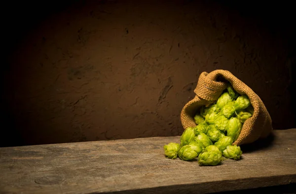 Beer. Still life with Vintage beer barrel and glass light beer. Fresh amber beer concept. Green hop and gold barley on wooden table. Ingredients for brewery. Brewing traditions