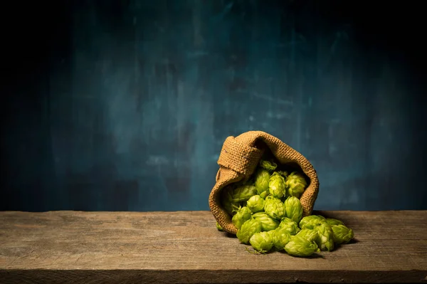 Cerveza. Bodegón con barril de cerveza Vintage y cerveza ligera de vidrio. Concepto de cerveza ámbar fresca. Lúpulo verde y cebada dorada sobre mesa de madera. Ingredientes para la cervecería. Las tradiciones cerveceras —  Fotos de Stock