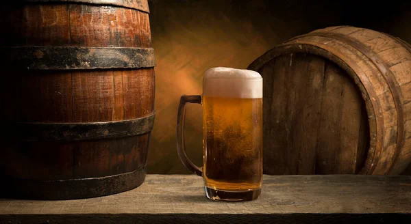 Sört. Csendélet Vintage sörhordóval és üveg világos sörrel. Friss borostyán sör koncepció. Zöld hop és arany árpa a fa asztalon. Hozzávalók a sörfőzdéhez. Sörfőzési hagyományok — Stock Fotó