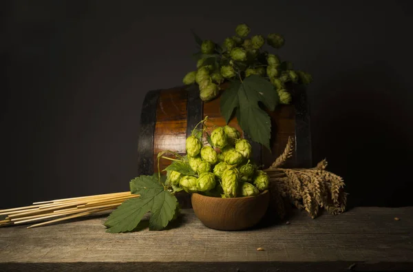 Beer. Still life with Vintage beer barrel and glass light beer. Fresh amber beer concept. Green hop and gold barley on wooden table. Ingredients for brewery. Brewing traditions