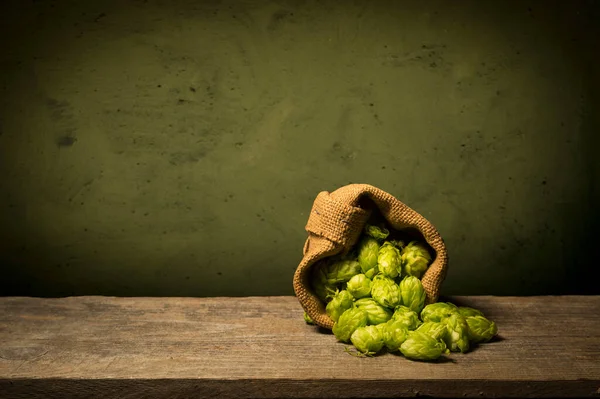 Cerveza. Bodegón con barril de cerveza Vintage y cerveza ligera de vidrio. Concepto de cerveza ámbar fresca. Lúpulo verde y cebada dorada sobre mesa de madera. Ingredientes para la cervecería. Las tradiciones cerveceras —  Fotos de Stock