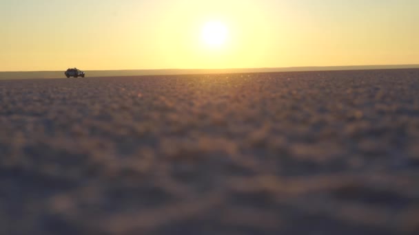 Paseos en coche sobre una superficie plana de arena contra el fondo del amanecer — Vídeos de Stock