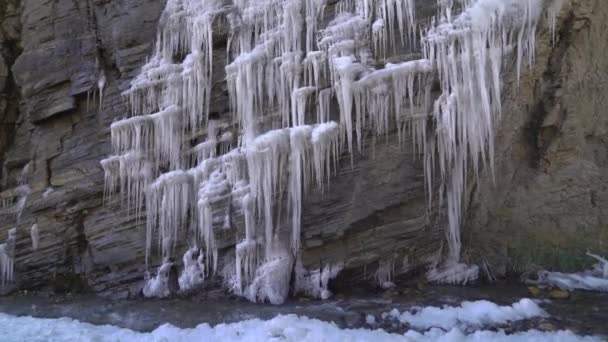Skála pokrytá rampouchy a ledem u horského potoka u ledovce — Stock video