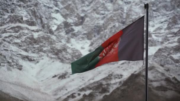 Bandeira do Afeganistão acenando no vento contra o pano de fundo de montanhas nevadas — Vídeo de Stock