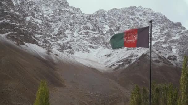 Афганский флаг, размахивающий на ветру на фоне снежных гор — стоковое видео