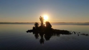 Uvildy 'nin güneyindeki bir dağ gölünde gün batımı. Sudaki yansıma. Gölün ortasındaki ada.. 