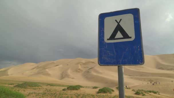 砂漠の砂丘を背景に道路標識をキャンプし — ストック動画