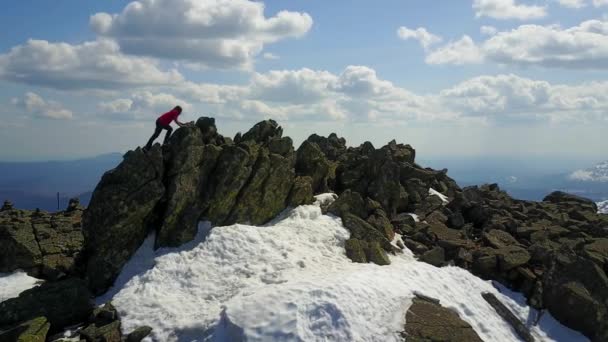 Chica en ropa roja hace la subida a la cima de la montaña — Vídeos de Stock