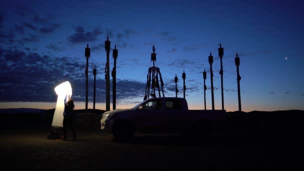 Dziewczyna instaluje oświetlenie w bazie o zmierzchu w Mongolii — Wideo stockowe