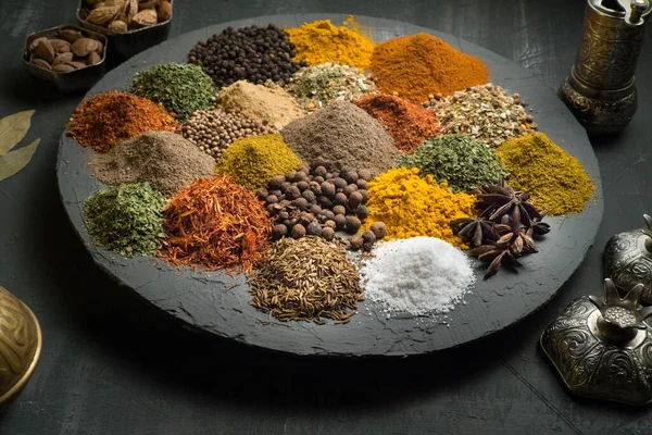 Doğu yemekleri ile çevrili koyu bir arka planda baharatlar, üst görünüm