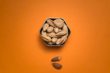 Turuncu kahverengi arka planda badem fıstığı ve fındıklı vazo.