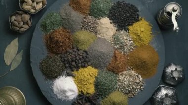 Çeşit çeşit baharatlar, yuvarlak bir yüzey üzerinde, karanlık bir zemin üzerinde, doğu yemekleri ile çevrili, üst görünüm