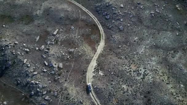 Vista superior de um carro dirigindo ao longo de uma estrada sinuosa através de um deserto de pedra no Cazaquistão — Vídeo de Stock