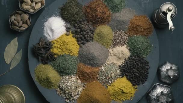 Kryddor i variation snurra på en rund yta på en mörk bakgrund omgiven av orientaliska rätter, ovanifrån — Stockvideo