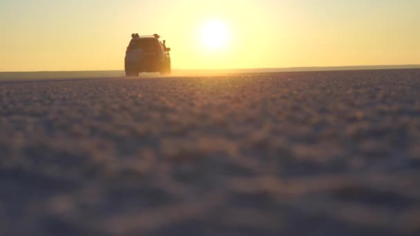 Το αυτοκίνητο ταξιδεύει από την κάμερα στον ήλιο σε μια επίπεδη επιφάνεια την αυγή — Αρχείο Βίντεο