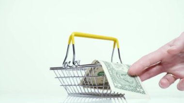 Erkek eli alır ve süpermarket sepetine bir dolar koyar.