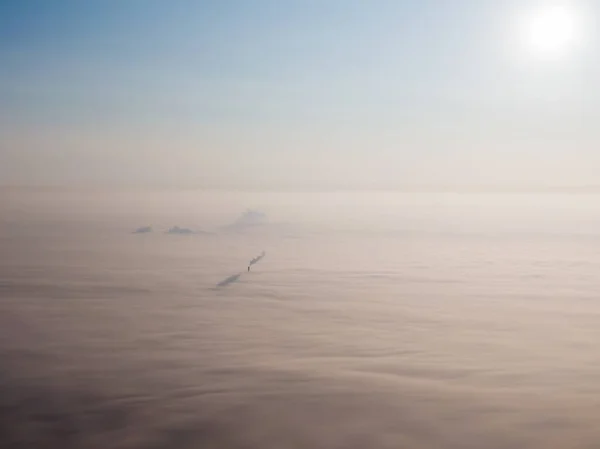 Bulutlarda şehrin hava manzarası. Bulutların sisli olduğu fabrikanın bacası. Yüksek kalite fotoğraf