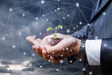 El bir işadamı bir bitki Filiz gökyüzüne karşı gösterir..