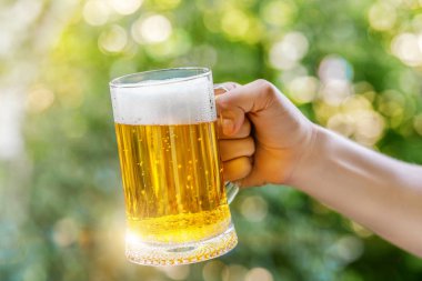 Adam bir bardak bira bulanık arka plan üzerinde tutar..