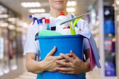 Temizlikçi kadın bir kova ve temizlik ürünleri ile deposudur.