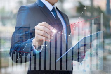 İşadamı bir grafik mali istatistiklerin bulanık bir arka plan üzerinde çizer..