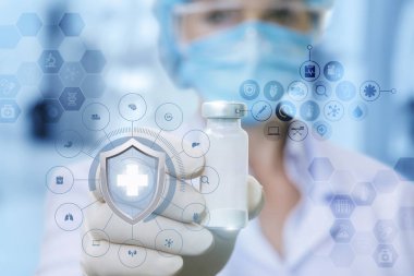 Kadın doktor tıbbi maskeli bir aşı lastik eldiven tarak içinde madical sembolleri ile çevrili kalkan arkasında onun elinde gösterilen.