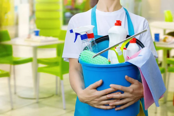 一名清洁妇女拿着一个蓝色的水桶 上面有化学品和整理的设施 — 图库照片