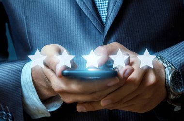 Bir iş adamı onun cep telefonu ekran ön planda yıldız semboller hattı ile temas ediyor. Derecelendirme kavramını.