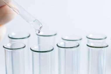 Bir laboratorian bir pipet bazı kimyasal madde amd test tüplerini kullanarak analiz yapıyor.