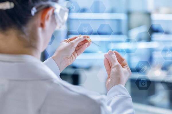 Лаборант работает над некоторыми исследованиями, используя пипетку и стеклянную поверхность на внутреннем фоне лаборатории. Концепция - это лаборатория исследователей
.