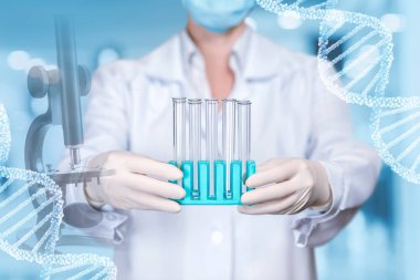 Maskeli bir laboratuar asistanı onun tarafın bir dizi test tüpleri laboratuvar arka plan ve dna modelleri ile mikroskop tutuyor.