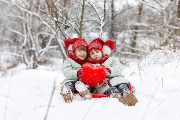 Twins Dziewczyna Siedzący Ziemi Śniegu Przytrzymanie Razem Jasne Czerwone Serce — Zdjęcie stockowe