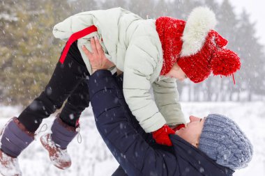 Bir anne kızının boş zamanlarında açık havada karlı kış parkta zevk kadar mutlu gülen çocuk yetiştirme ile oynuyor. Kış açık Aile aktivitesi bir kavramdır.