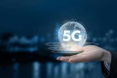 Bir el biult içinde 5 g tabelaya gece şehir arka plan ile kablosuz bağlantıların olan dijital bir küre tutuyor.